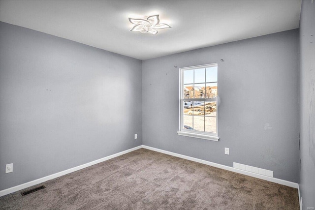 carpeted empty room featuring baseboards and visible vents