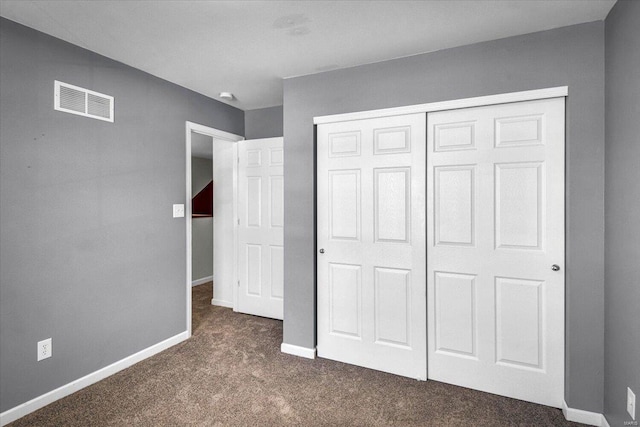 unfurnished bedroom with a closet, baseboards, visible vents, and dark colored carpet