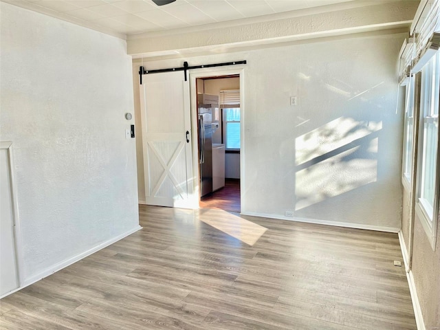 empty room featuring a barn door and hardwood / wood-style flooring