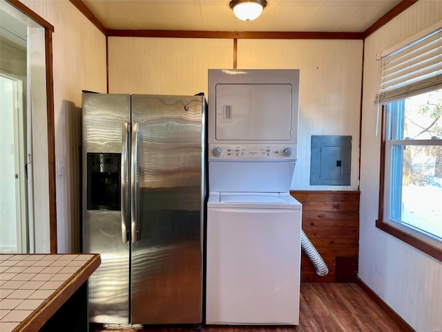 kitchen featuring electric panel, stacked washer / dryer, dark hardwood / wood-style floors, crown molding, and stainless steel fridge