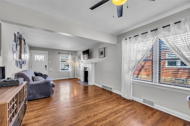 living room featuring ceiling fan, a fireplace, and hardwood / wood-style flooring