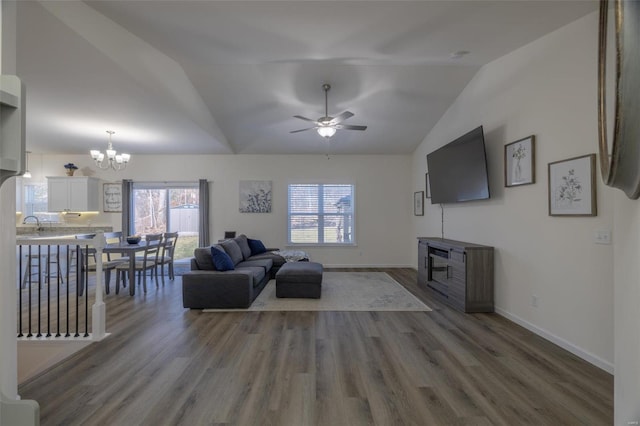 living room with ceiling fan with notable chandelier, vaulted ceiling, and dark hardwood / wood-style floors