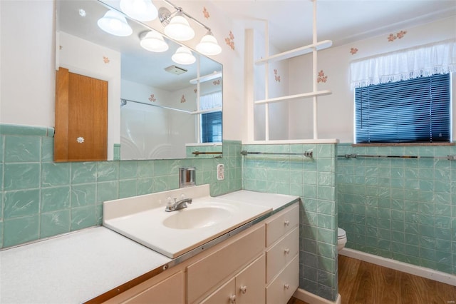 bathroom featuring toilet, wood-type flooring, a shower, vanity, and tile walls