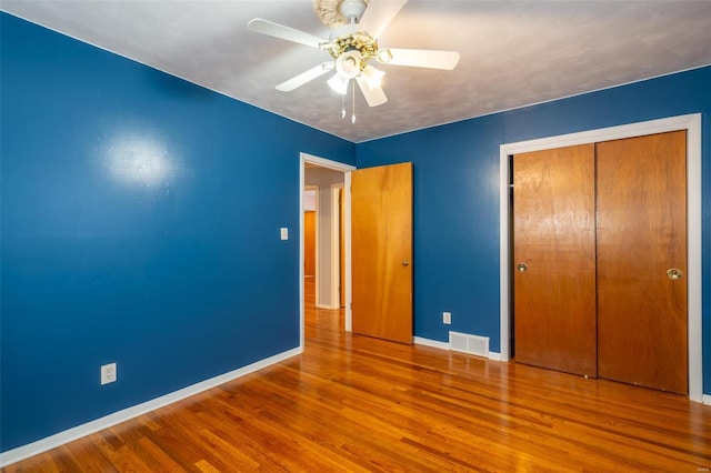 unfurnished bedroom with ceiling fan, a closet, and hardwood / wood-style flooring