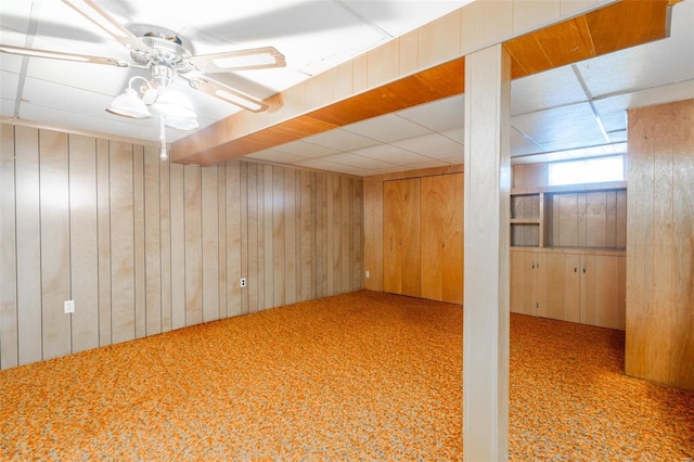 basement with ceiling fan, wooden walls, and carpet floors