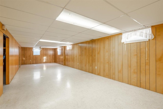 basement featuring a paneled ceiling and wooden walls