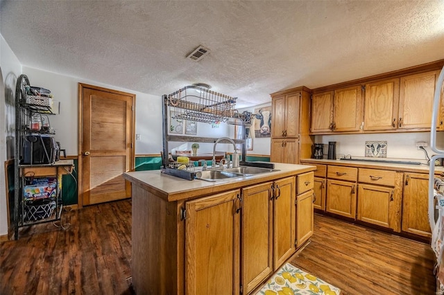 kitchen with sink, a center island with sink, a textured ceiling, and dark hardwood / wood-style flooring