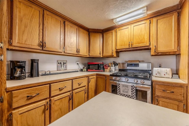 kitchen featuring stainless steel gas range oven and a textured ceiling