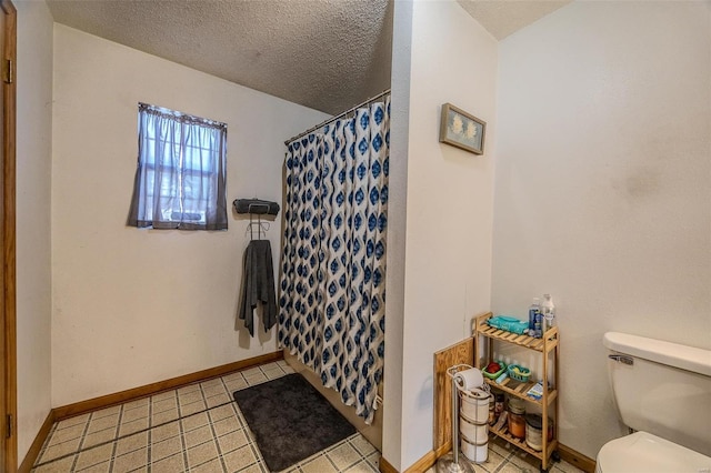 bathroom featuring toilet, a shower with shower curtain, and a textured ceiling