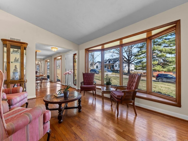 living room featuring vaulted ceiling, plenty of natural light, wood-type flooring, and a notable chandelier