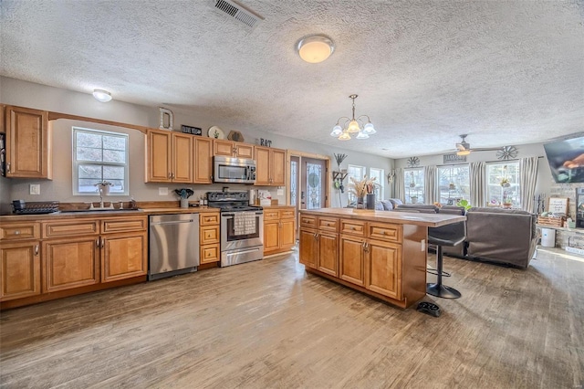 kitchen featuring a textured ceiling, pendant lighting, stainless steel appliances, a breakfast bar area, and sink