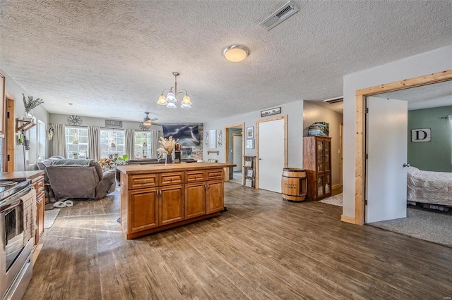 kitchen featuring decorative light fixtures, a center island with sink, stainless steel electric range, ceiling fan with notable chandelier, and wood-type flooring