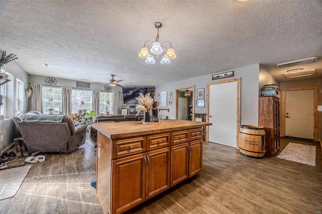 kitchen featuring a textured ceiling, hanging light fixtures, a center island, and ceiling fan with notable chandelier