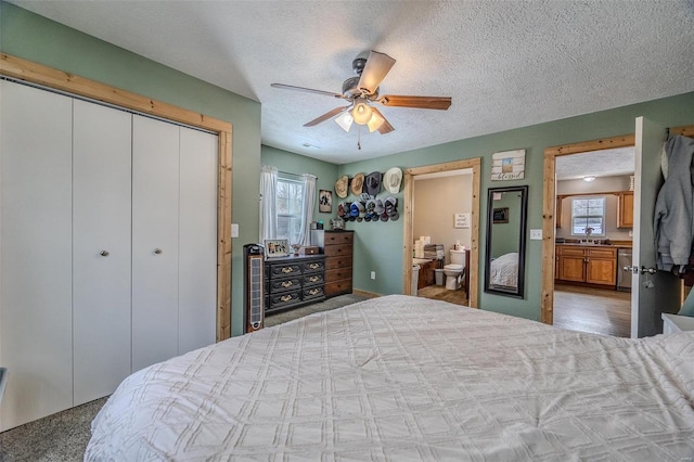 bedroom featuring connected bathroom, a closet, ceiling fan, a textured ceiling, and sink