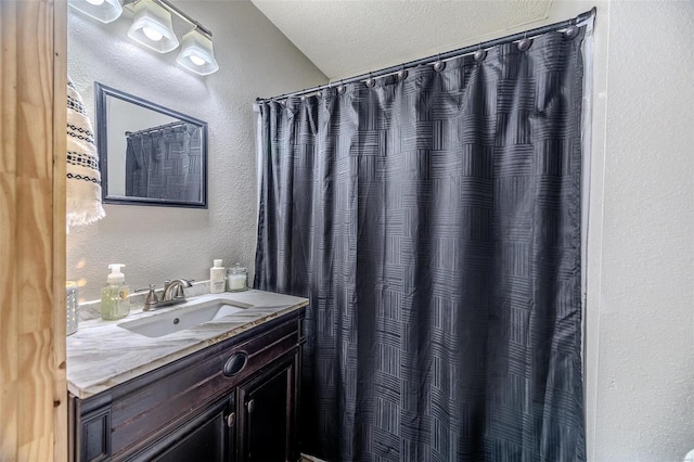 bathroom with a textured ceiling, a shower with shower curtain, and vanity