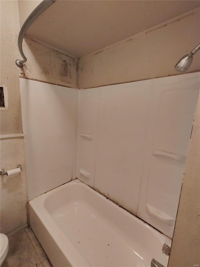 bathroom featuring tile patterned flooring, shower / bathtub combination, and toilet