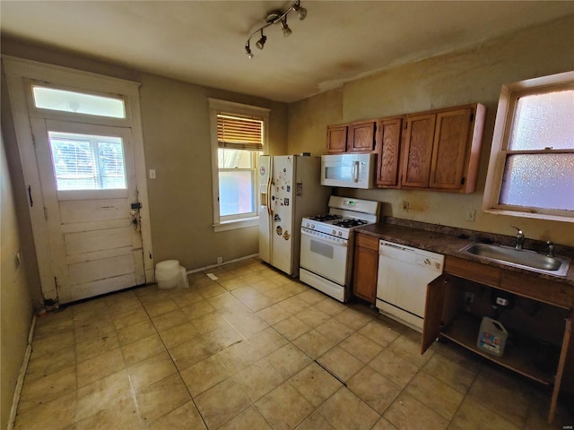 kitchen with white appliances, track lighting, and sink