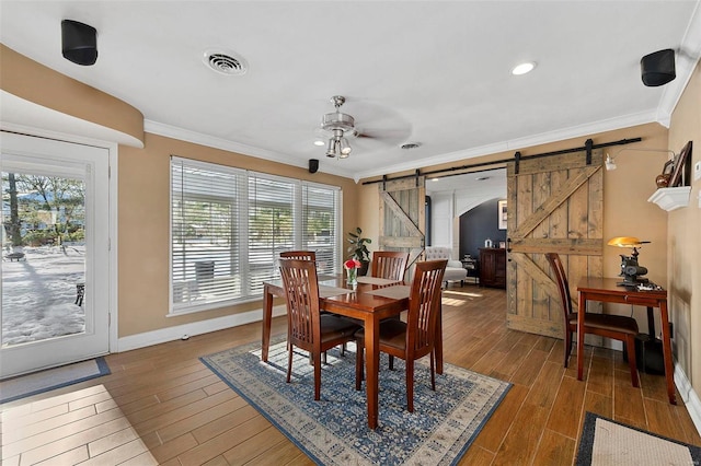 dining room with ceiling fan, crown molding, a healthy amount of sunlight, and a barn door