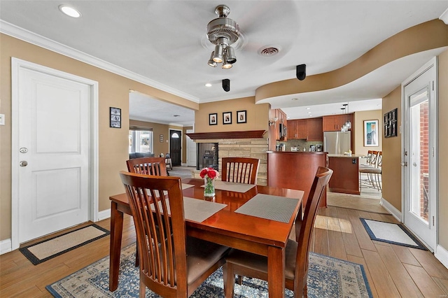 dining space with ceiling fan, light hardwood / wood-style floors, and crown molding