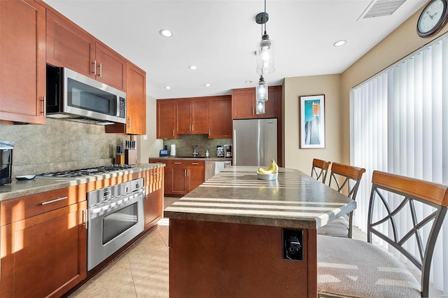 kitchen featuring pendant lighting, a center island, stainless steel appliances, a breakfast bar area, and light tile patterned flooring