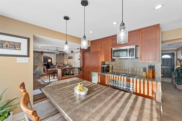 kitchen with stainless steel appliances, a kitchen bar, tasteful backsplash, hanging light fixtures, and a barn door