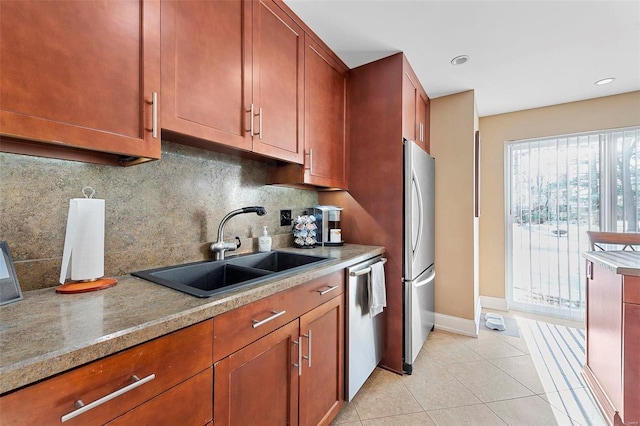 kitchen featuring stainless steel appliances, sink, light tile patterned floors, decorative backsplash, and light stone countertops