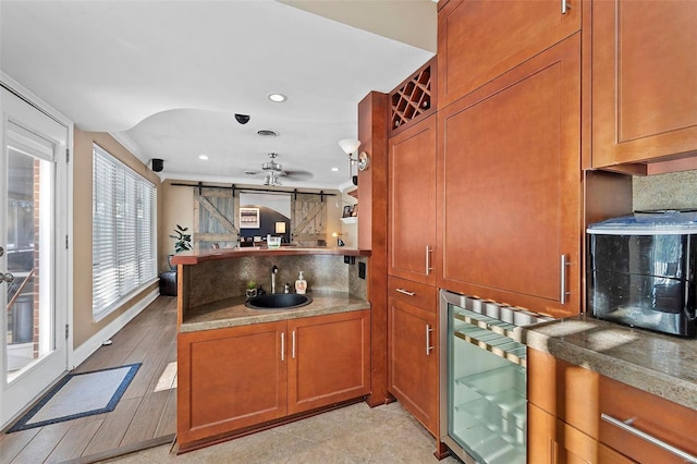 kitchen with sink, kitchen peninsula, decorative backsplash, a barn door, and wine cooler