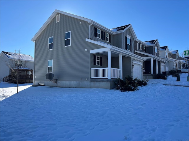 view of snow covered exterior featuring covered porch and a garage