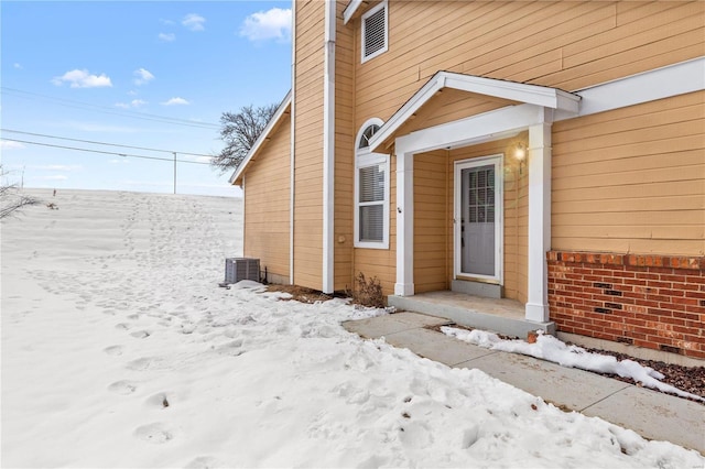 snow covered property entrance featuring cooling unit