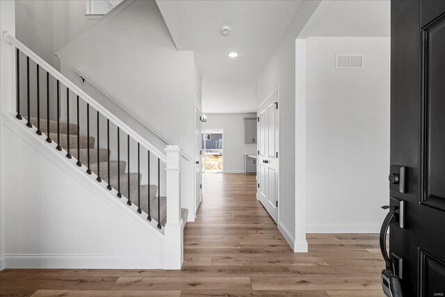 foyer entrance with light wood-style floors, stairway, visible vents, and baseboards