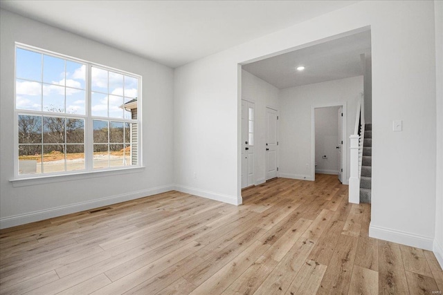 empty room with visible vents, light wood finished floors, and a healthy amount of sunlight