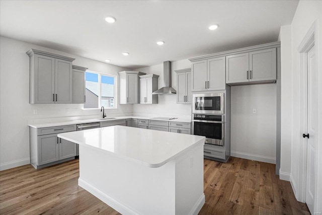 kitchen featuring wall chimney range hood, built in microwave, oven, and gray cabinets
