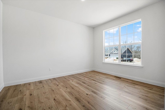 unfurnished room with wood finished floors, baseboards, and visible vents