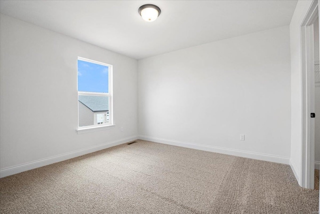 empty room featuring carpet flooring, visible vents, and baseboards