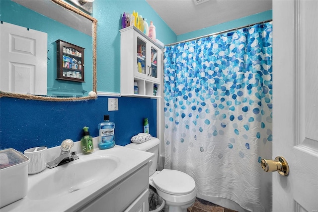 bathroom featuring a textured ceiling, toilet, vanity, and walk in shower