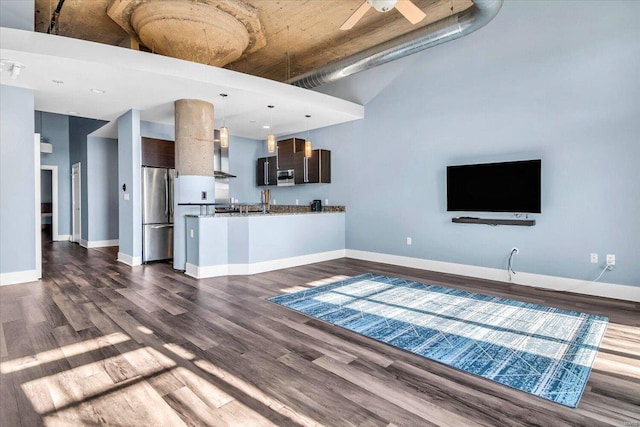 unfurnished living room featuring a high ceiling, ceiling fan, and dark hardwood / wood-style floors