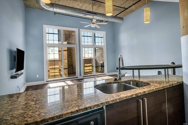 kitchen with sink, decorative light fixtures, and stone counters