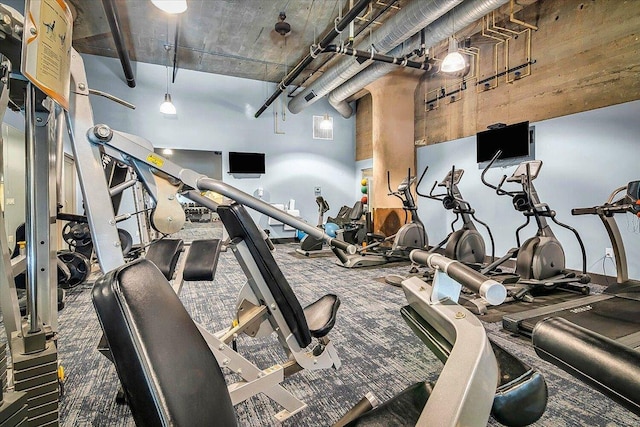 exercise room with a towering ceiling and carpet