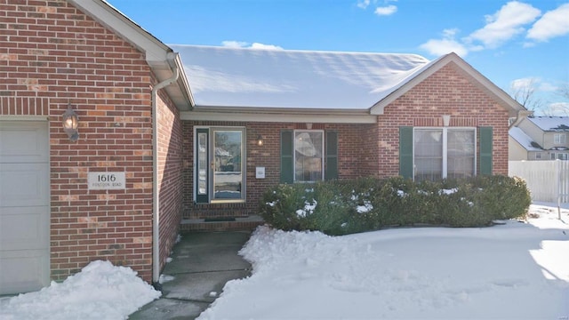 snow covered property entrance featuring a garage