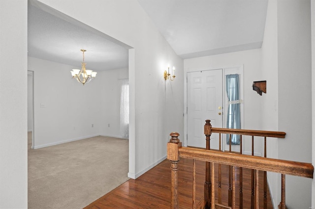 carpeted foyer featuring a notable chandelier and lofted ceiling