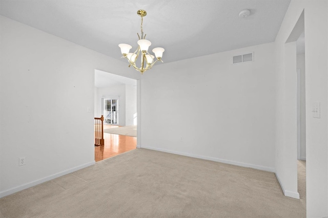 unfurnished room featuring light colored carpet and a notable chandelier