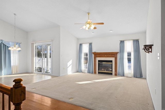 unfurnished living room featuring ceiling fan with notable chandelier and light wood-type flooring