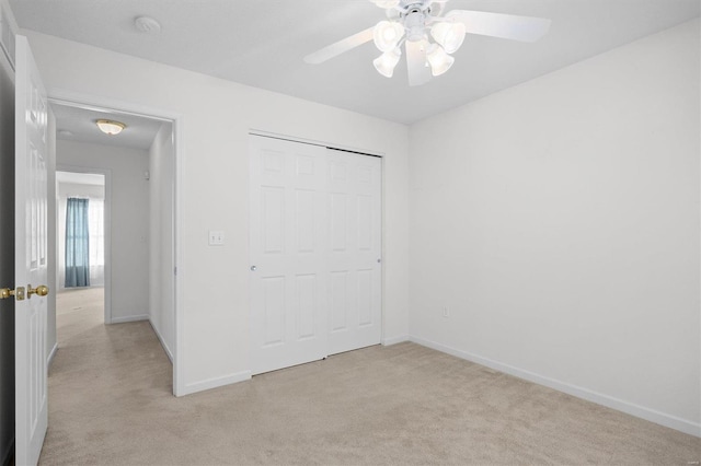 unfurnished bedroom featuring ceiling fan, a closet, and light carpet