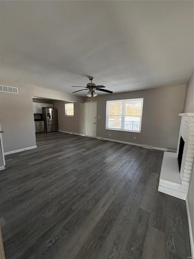 unfurnished living room featuring ceiling fan, a fireplace, and dark wood-type flooring