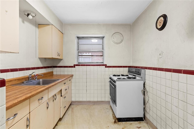 kitchen with sink, tile walls, white range with gas cooktop, and cream cabinetry