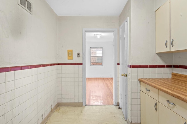 interior space with tile walls and cream cabinetry