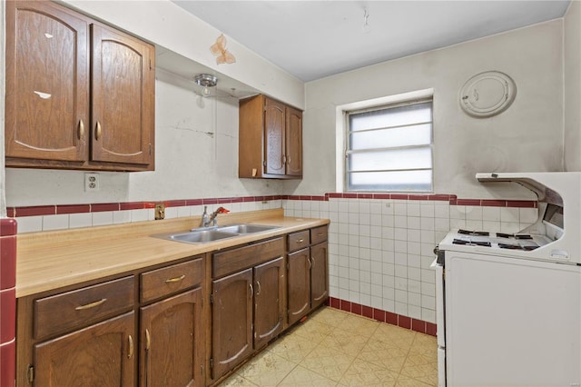 kitchen with tile walls, white gas range, and sink