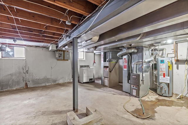 basement featuring water heater, heating unit, and independent washer and dryer