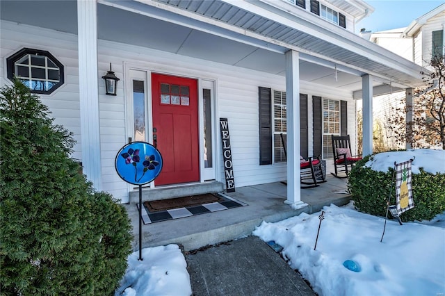 snow covered property entrance with a porch