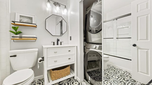 full bathroom featuring toilet, enclosed tub / shower combo, tile patterned floors, vanity, and stacked washer and clothes dryer